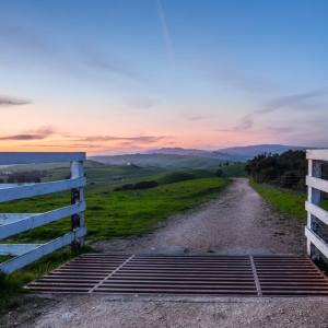 A small bridge with a sunset and a field behind it
