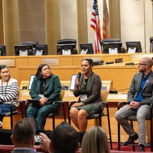 Four people seated, one speaking into a microphone