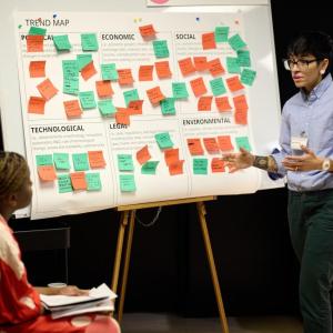 Someone presenting, using colorful sticky notes on a board