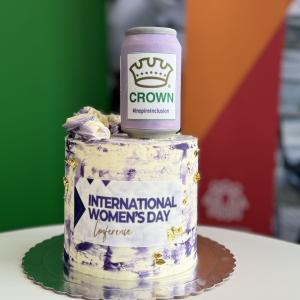 A white and purple cake that has "international women's day conference" on the front 