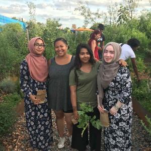 People standing together and smiling with greenery behind them