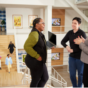 Three Bath & Body Works associates stand together at the top of a staircase talking at the company’s headquarters in Columbus, Ohio.  