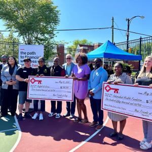People standing together, holding two oversized checks