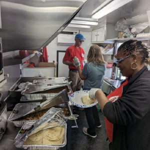 People serving food in the back of  the FedEx canteen truck