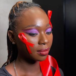 Person with purple eye makeup and red ribbons on their face