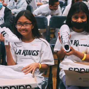 Two students showing off their new sneakers provided by the LA Kings and Shoes That Fit.