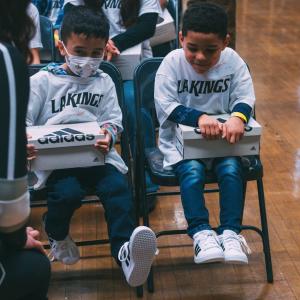 Students from Grant Elementary in Los Angeles, CA smiling as they try on their new shoes.