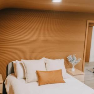 Bedroom of the 3D printed house. Neutral colors. Two bedside tables and bed next to a paneled door.