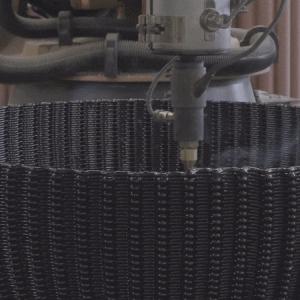 3D printer creating a piece of furniture with hot, black liquid material.