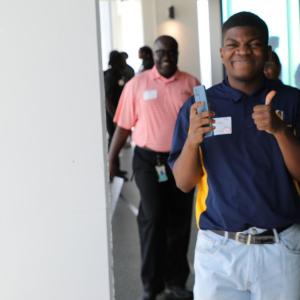 People walking through a corridor, one person smiling at the camera with their thumbs up
