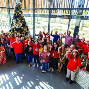 People waving by a holiday tree