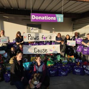 A large group photo of people holding up signs that reads "paws for a cause:"