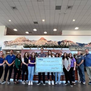 People posing together, holding a large check