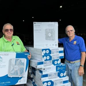 People standing next to stacks of new fans in boxes