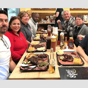 People smiling, sitting at a dining table with food in front of them