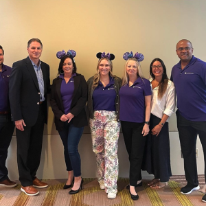 7 people standing inside together wearing purple, three with purple mouse ears