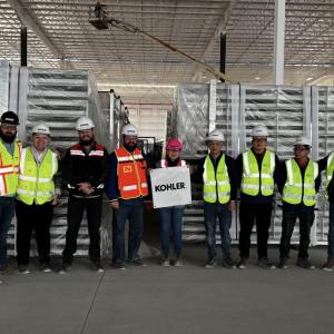 Group standing together in manufacturing plant wearing reflective vests