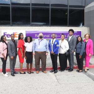 A group of people stood in a line in front of a FedEx banner