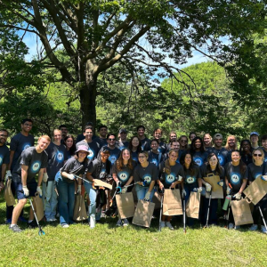 A group of people in Motorola t-shirts posing and smiling together under trees