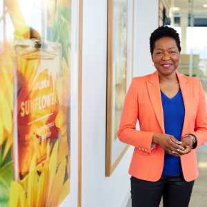 A person in an orange jacket standing in a hallway next to large photographs of Bath & Body Works products