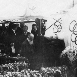 People under a tent near Olympic flags in 1924