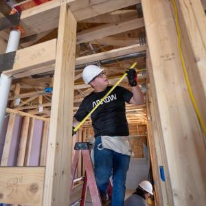 A person measuring part of a frame inside a house