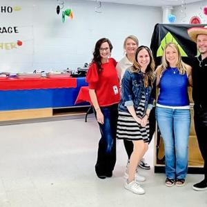 Five people standing together next to sign, "Nacho Average Teacher"