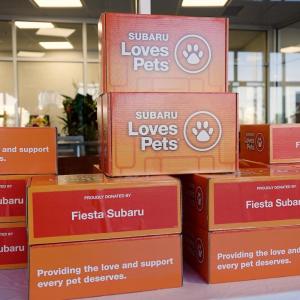 a stack of orange boxes that say "Subaru Loves Pets"