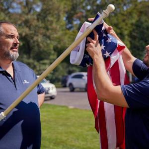 two people putting up American flag
