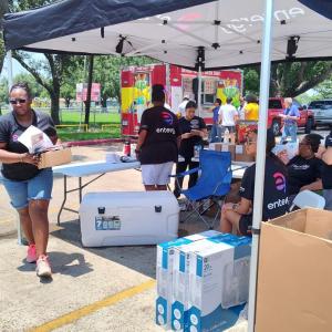 People outside under a tent distributing fans