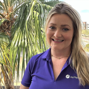 Smiling person wearing purple with a palm tree behind them
