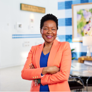 A person in an orange jacket standing in a hallway next to large photographs of Bath & Body Works products