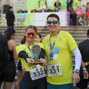 Two participants celebrate with medals and an award at the DP World-sponsored race in Santos.