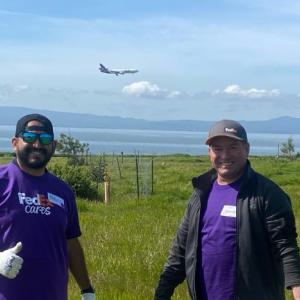 Two FedEx team members stood in a field