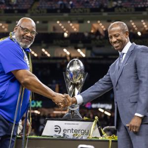 people shaking hands in front of a trophy
