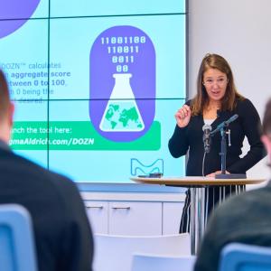 Woman standing at podium presents on "Green Chemistry" to an audience. 