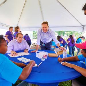 CEO stands over table teaching students