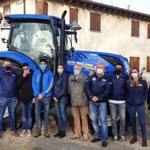 New Holland team in front of blue tractor