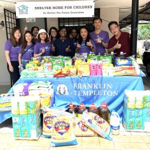 Group of Kuala Lumpur volunteers standing behind table piled with supplies