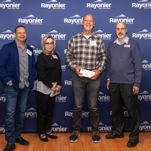 Four people standing together, one holding a check