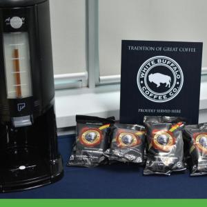 Four packets of coffee next to a coffee maker