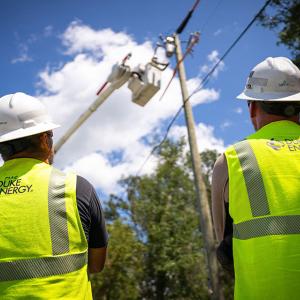 Two workers in hard hats and reflective vests shown from the back