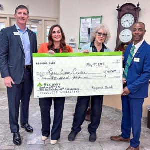 4 people holding a large check
