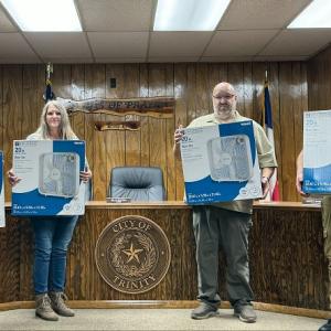 4 people posing, each holding a boxed fan