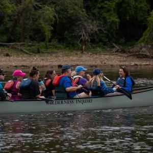 Many people in a canoe going downriver
