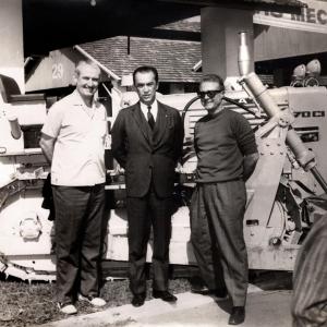 old photo of three people in front of bulldozer