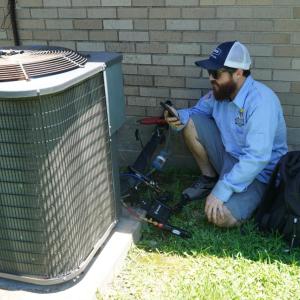 A worker next to an outdoor HVAC unit