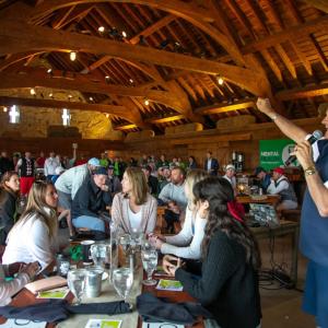 A person giving a speech to others during a meal inside a wooden building