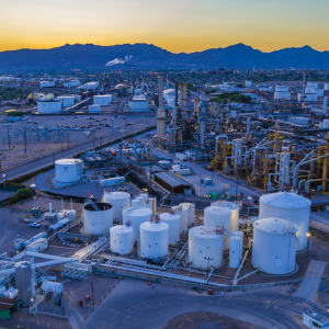 oil refinery in the desert at dawn, a mountain range on the horizon