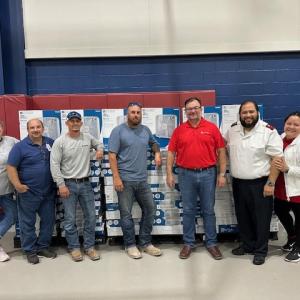 People standing in front of stacks of new fans